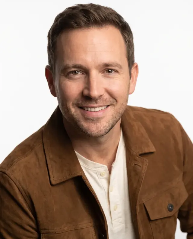 Actor headshot of a man in a brown suede jacket on a white backdrop