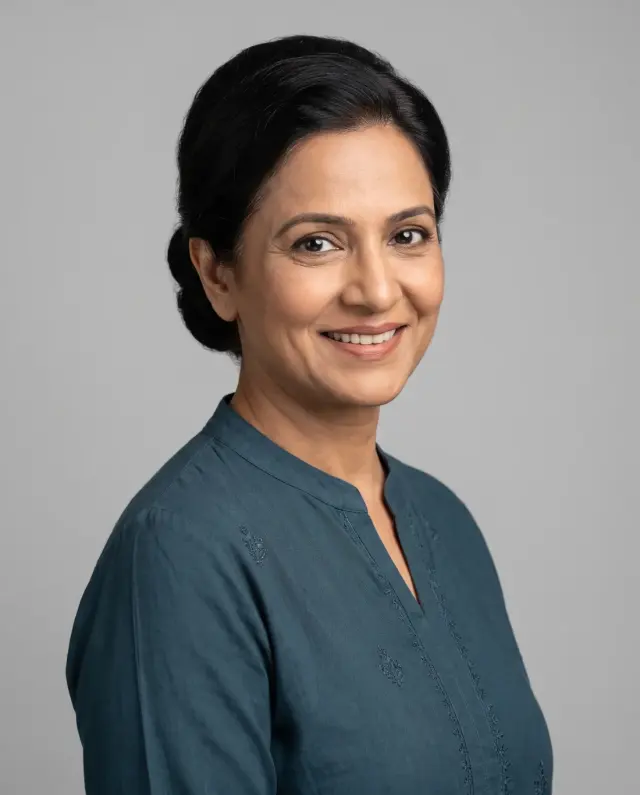Professional headshot of a woman with her hair pulled back in a teal tunic on a light grey backdrop