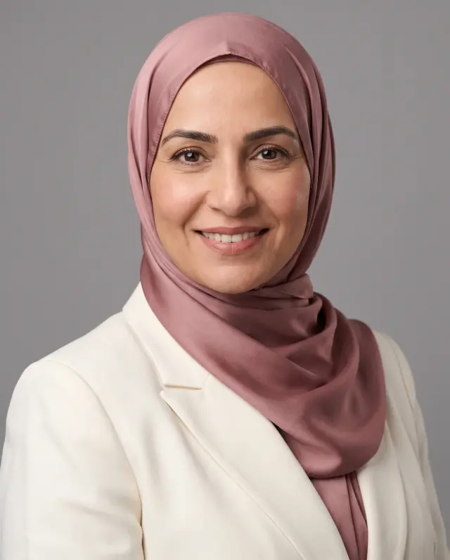 Professional headshot of a woman in a mauve satin hijab and cream blazer on a grey backdrop