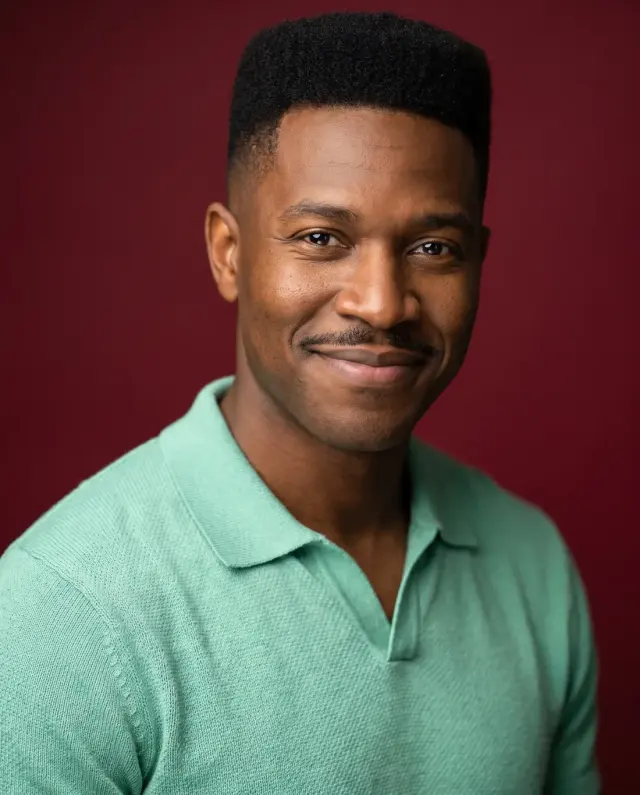 Actor headshot of a man in a mint knit polo on a deep red backdrop