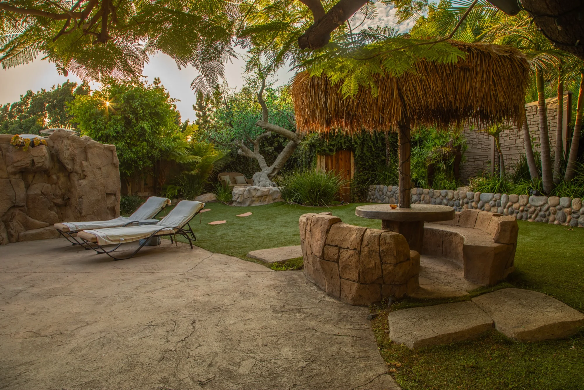 Loungers and a stone table under a palapa at The Enchanted Manor