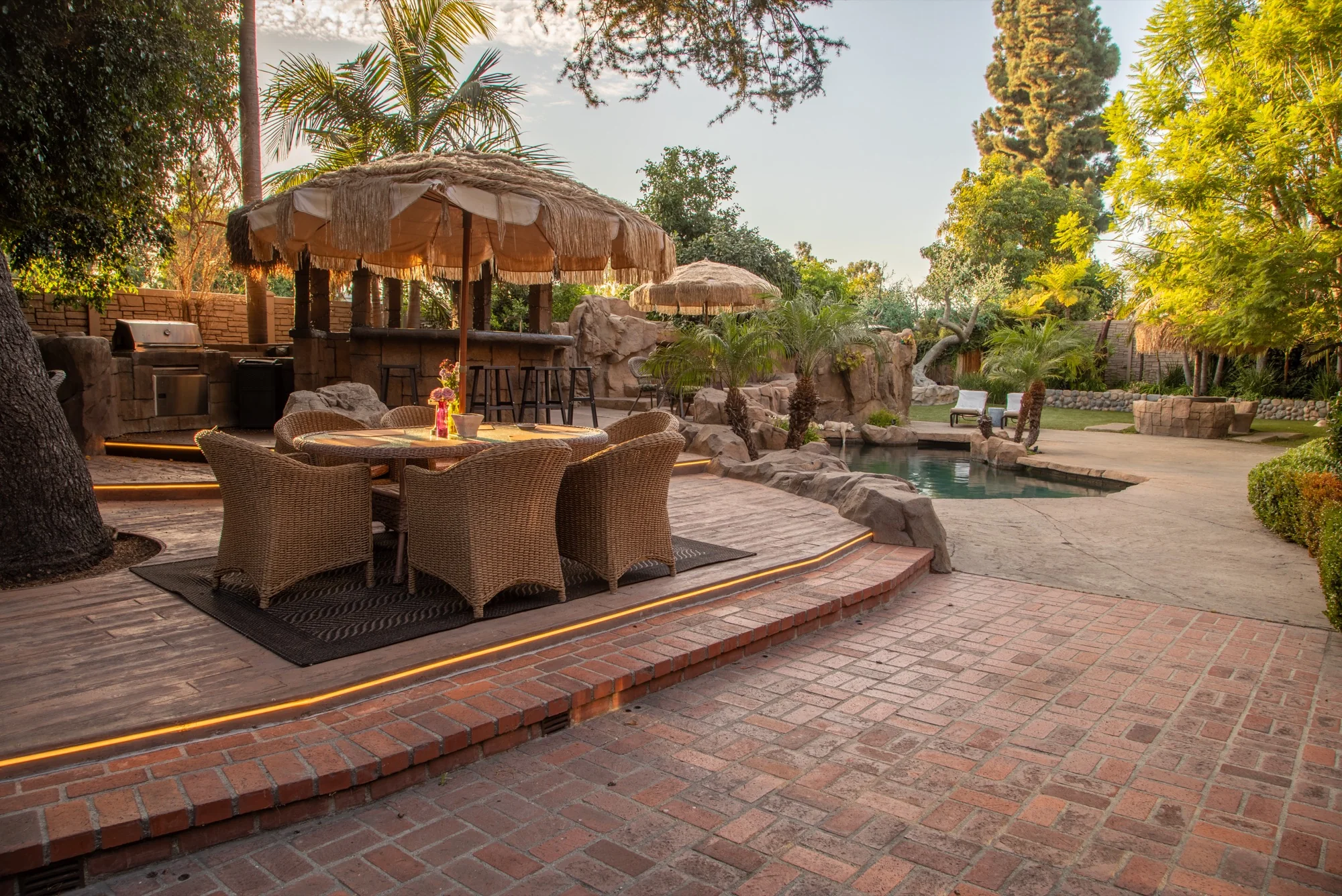 A dining table under the palapas beside the pool at The Enchanted Manor