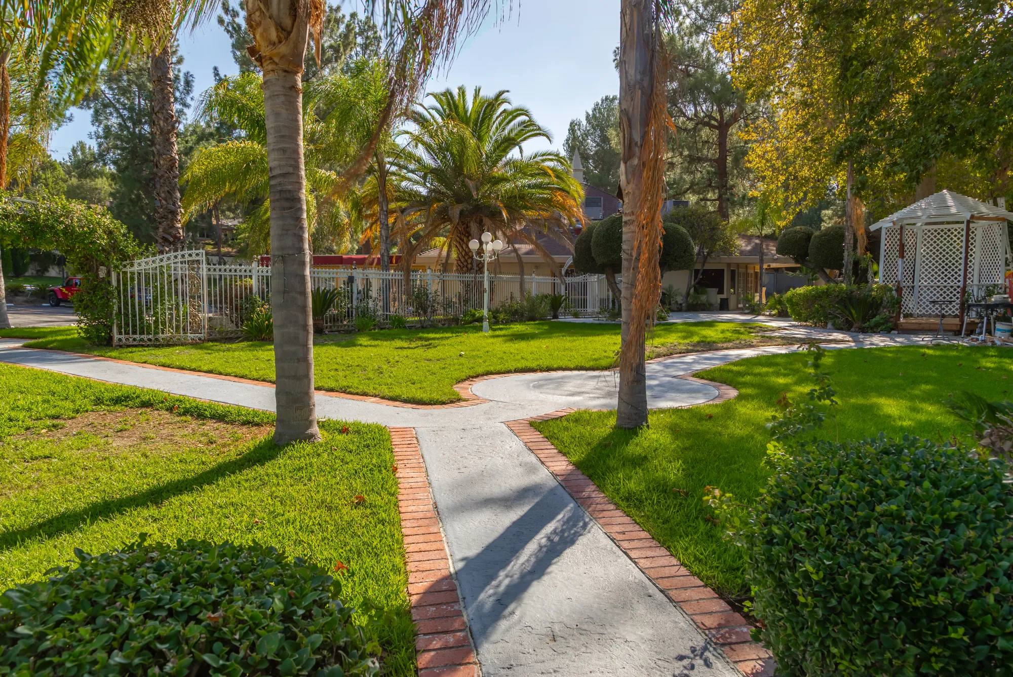 A brick-edged path crossing the lawn between palms at Kelly's Wedding Garden