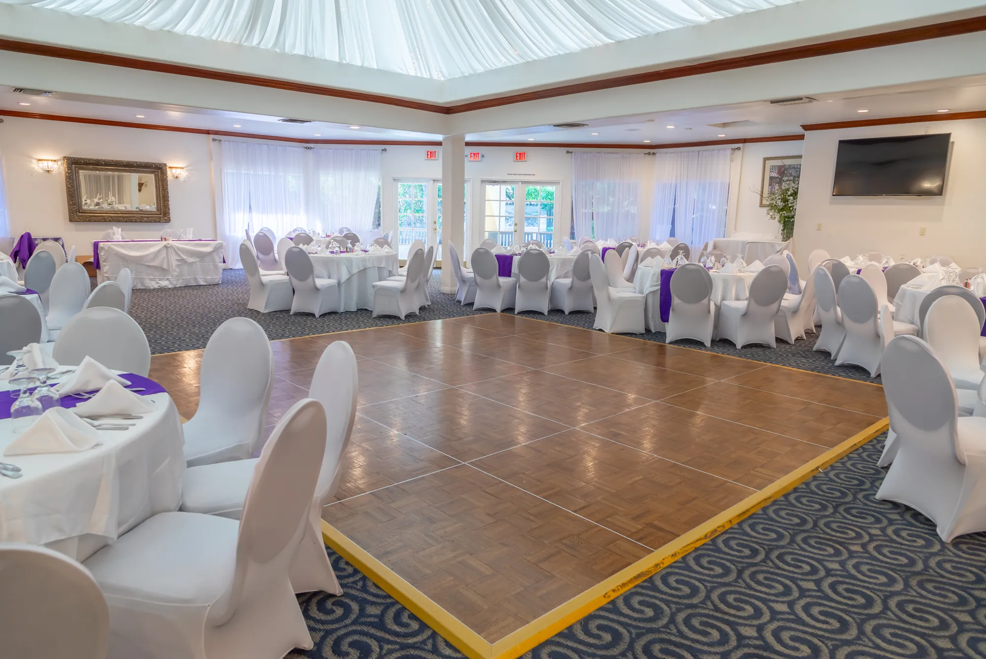 The wood dance floor surrounded by round tables at Kelly's Wedding Garden