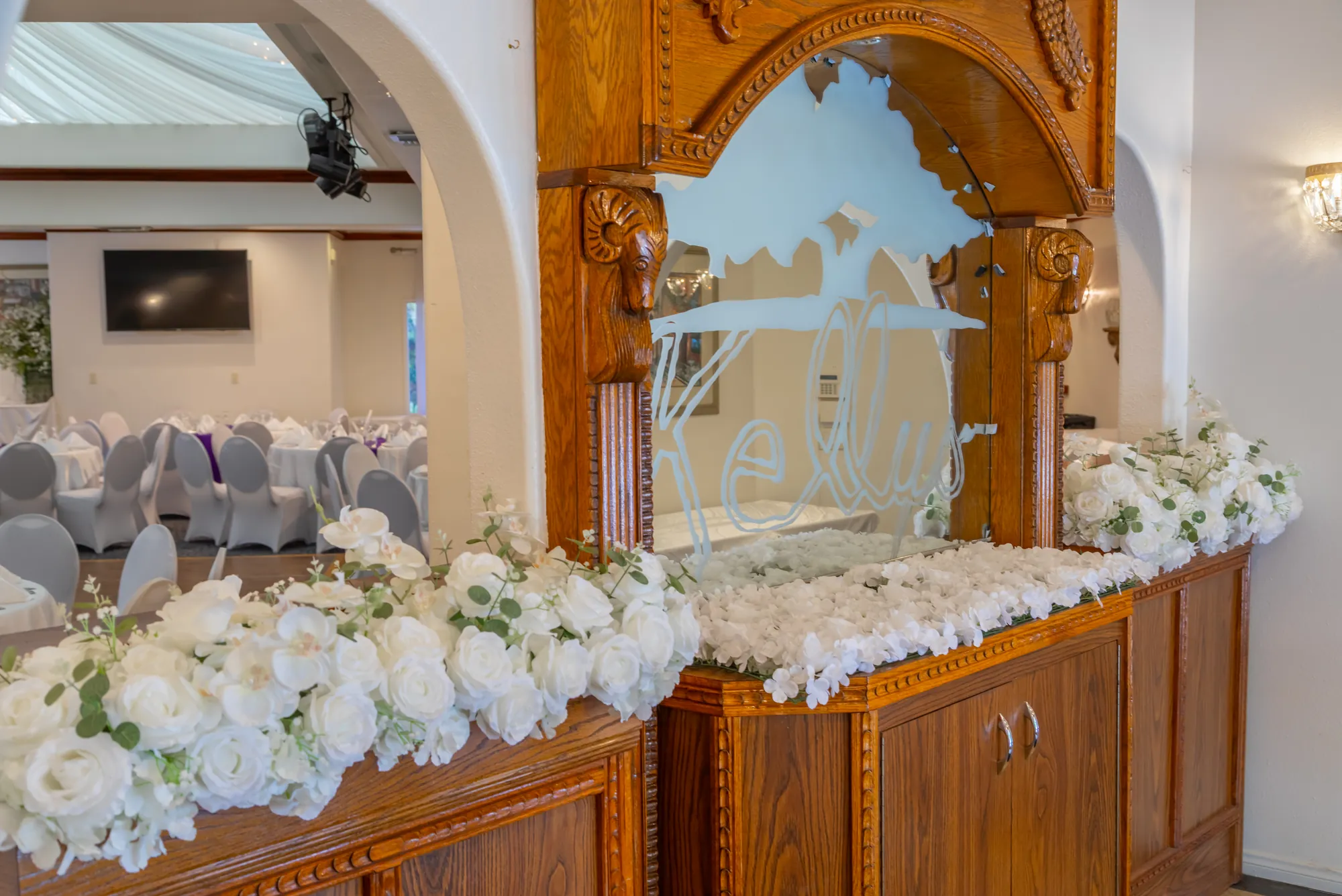 The etched Kelly's glass panel dressed with white roses at the entry to the banquet room