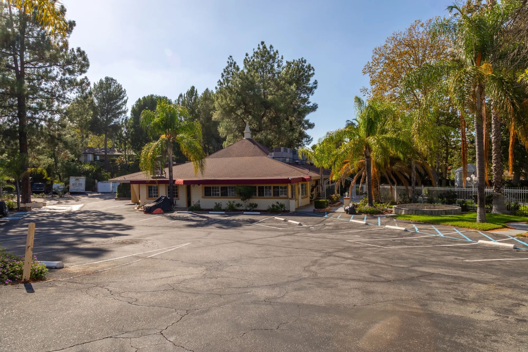 The banquet building seen across the forecourt between palms and pines at Kelly's Wedding Garden