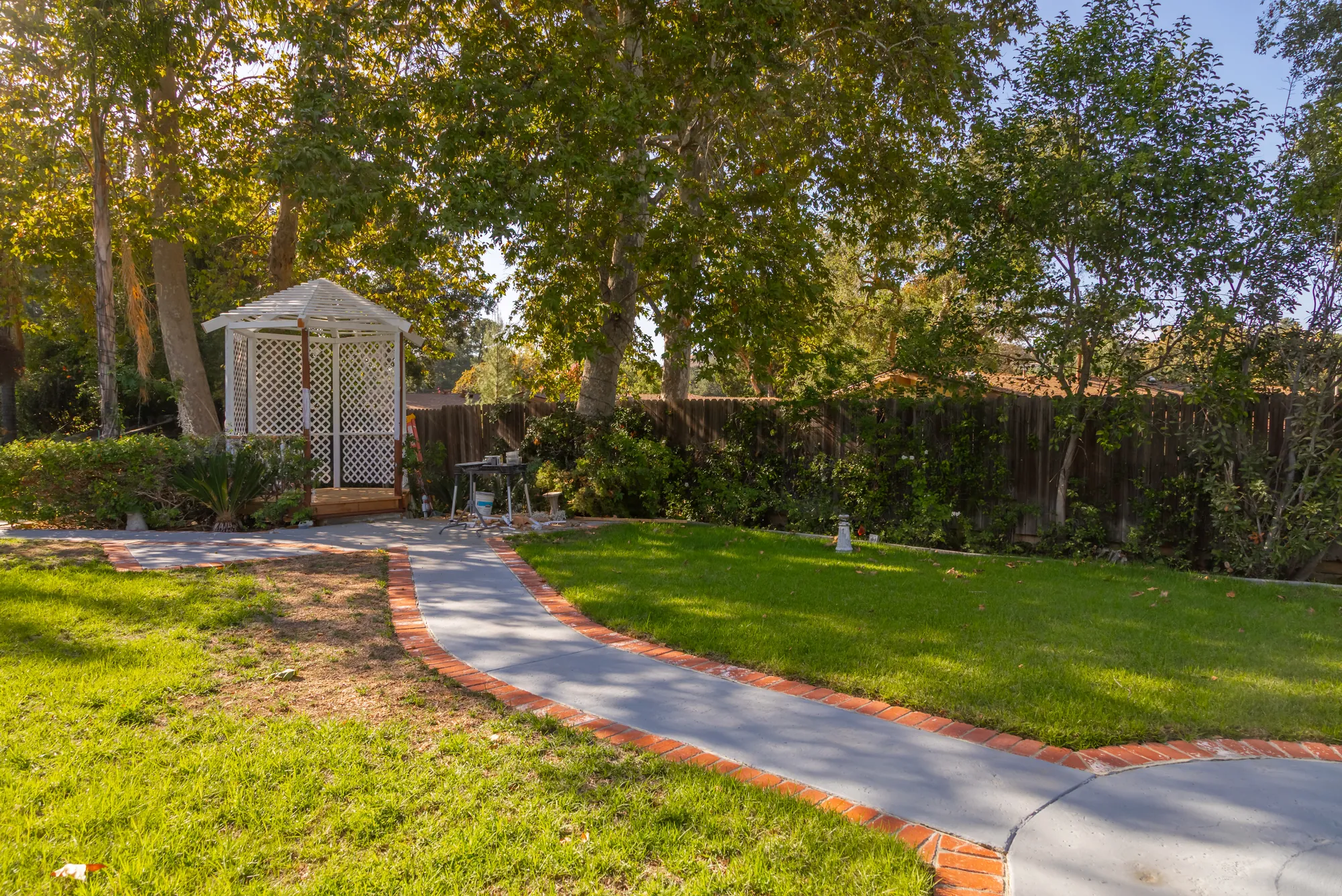 The white lattice gazebo at the far end of the lawn at Kelly's Wedding Garden