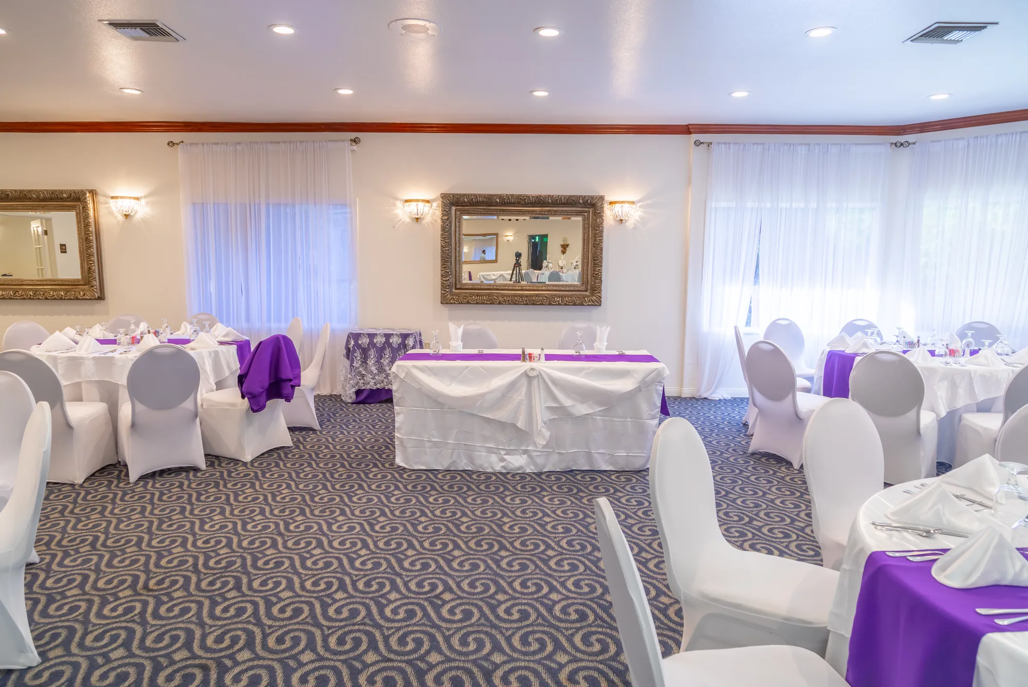 A draped table beneath the gilt mirror and sheer curtains at Kelly's Wedding Garden