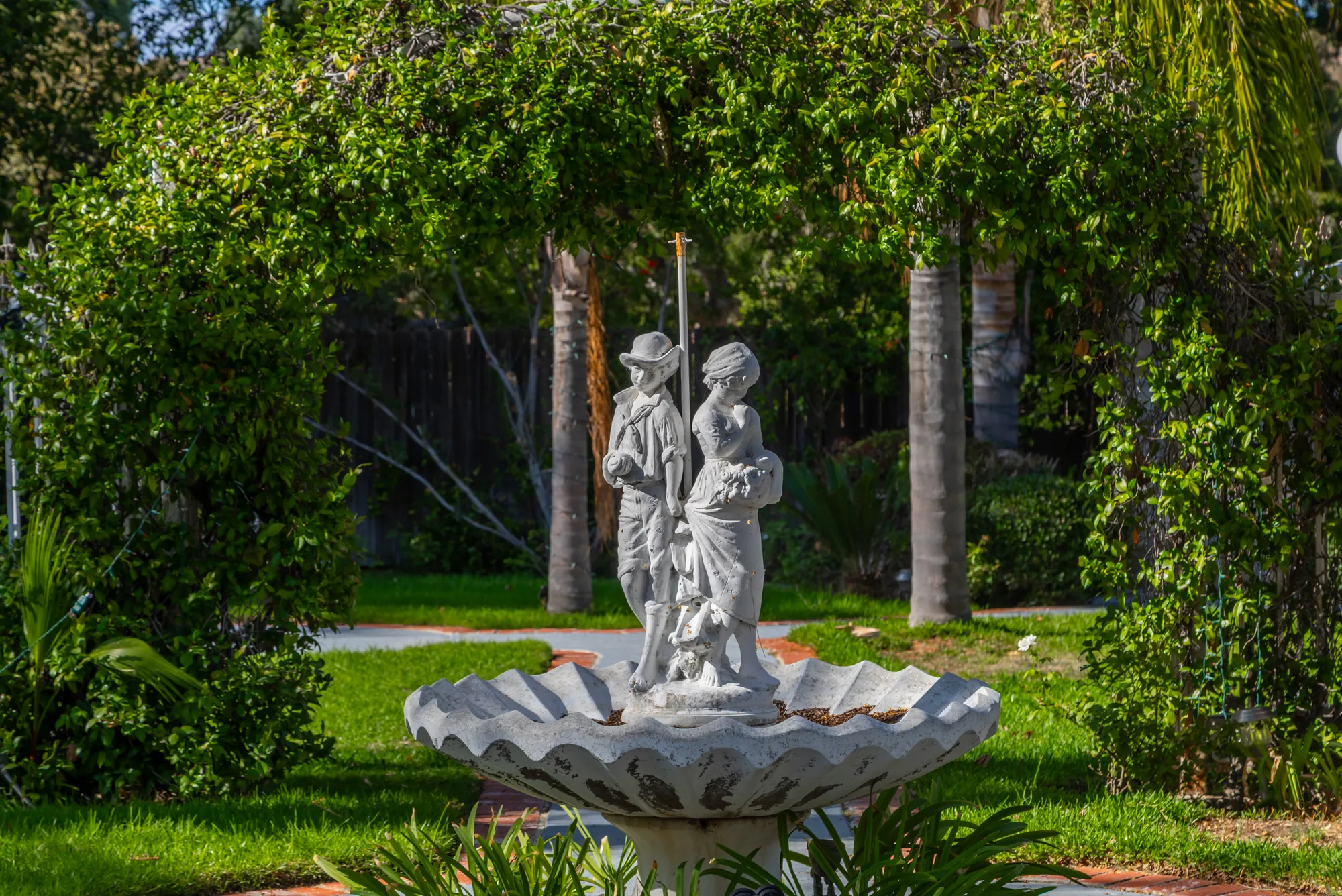 The courting-couple statue fountain under the green arbor at Kelly's Wedding Garden