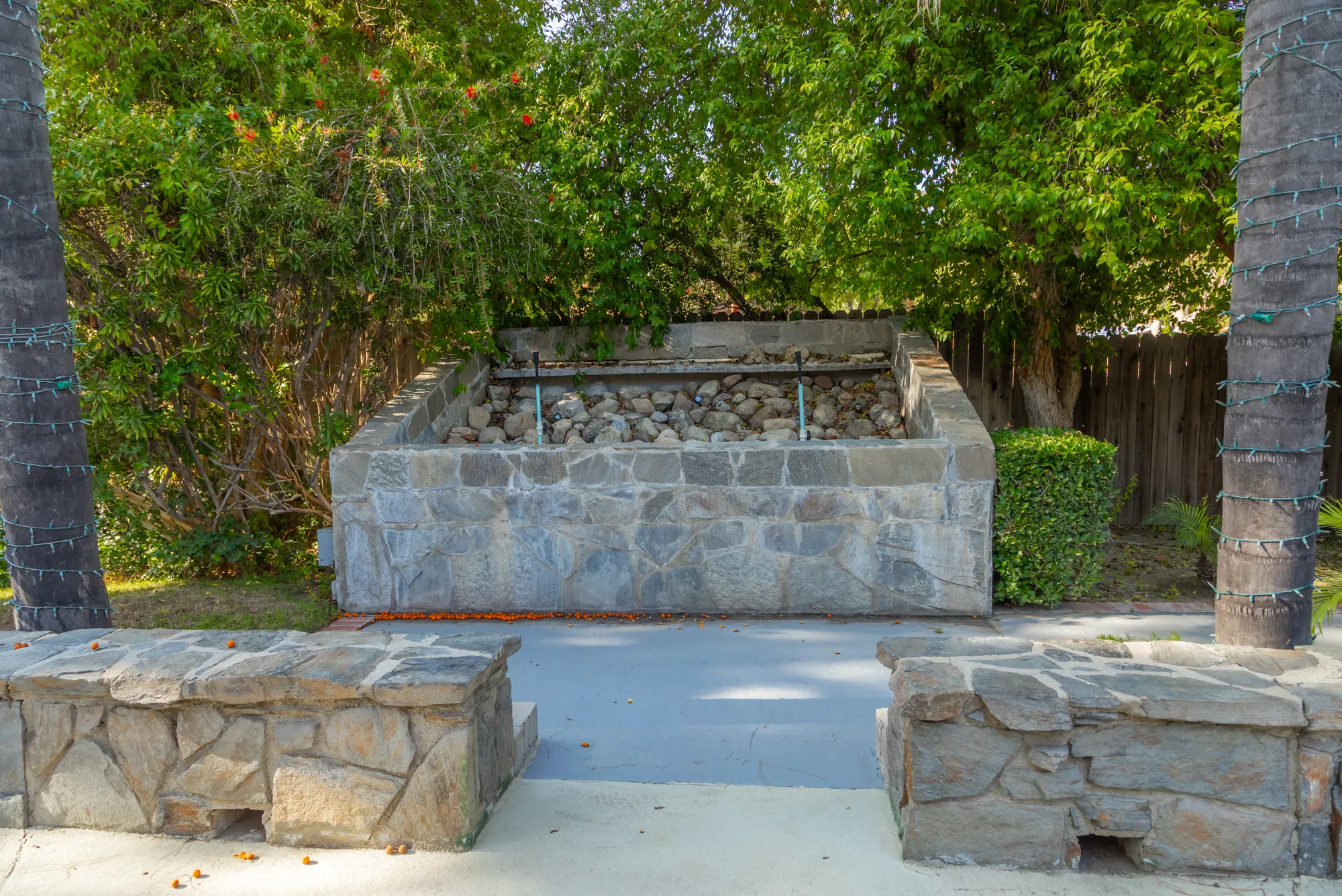 The stone water feature and low stone walls beside the patio at Kelly's Wedding Garden