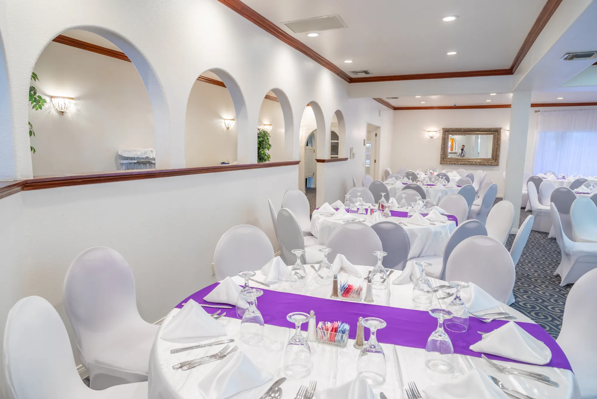 A place setting with a purple runner beside the arched entry wall at Kelly's Wedding Garden