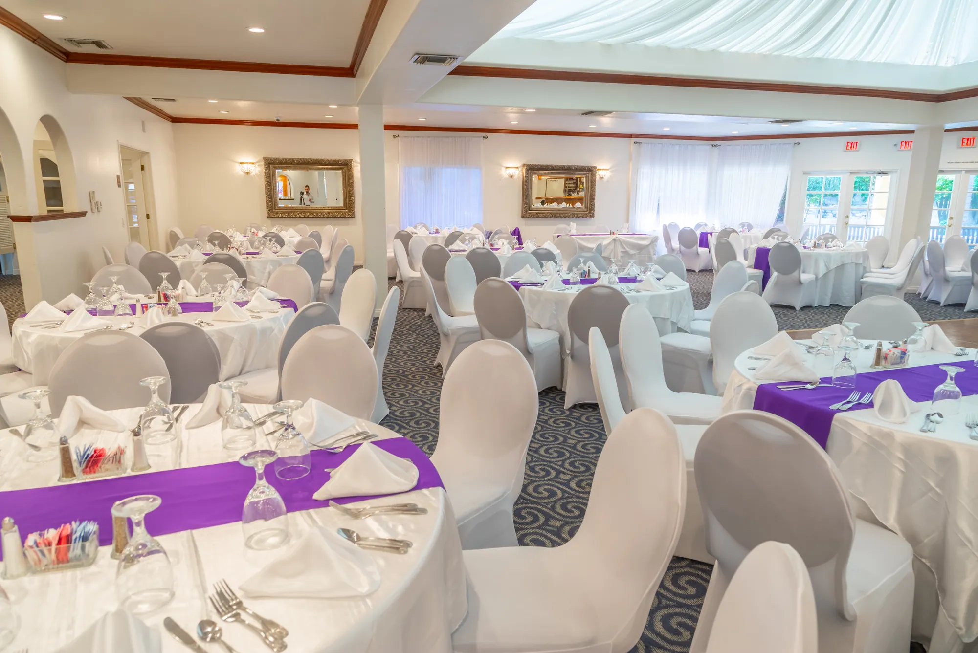 Round tables with purple runners beside the arched wall niches at Kelly's Wedding Garden