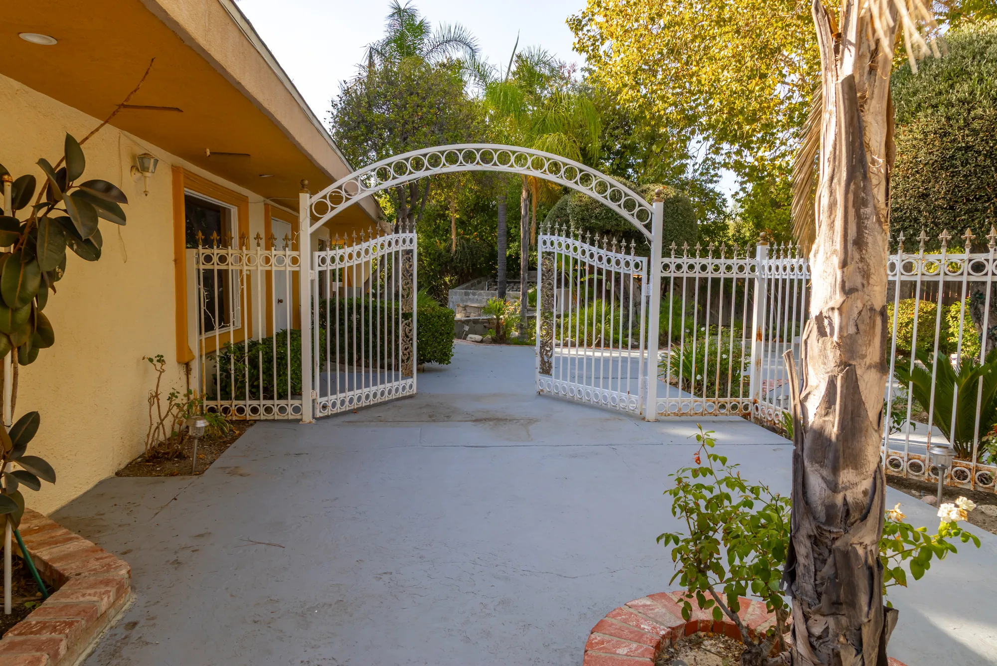 The arched white iron gate that opens into the garden at Kelly's Wedding Garden