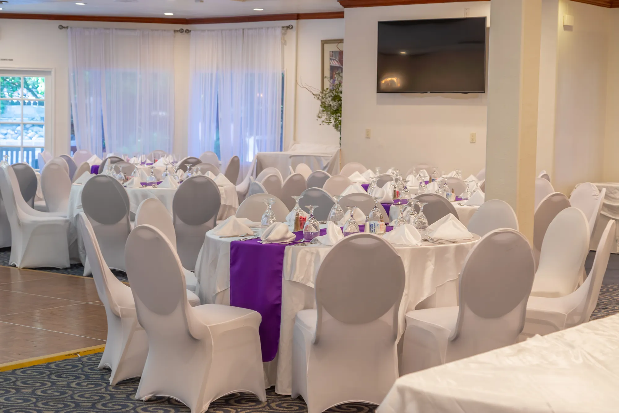 Tables by the curtained windows in the banquet room at Kelly's Wedding Garden