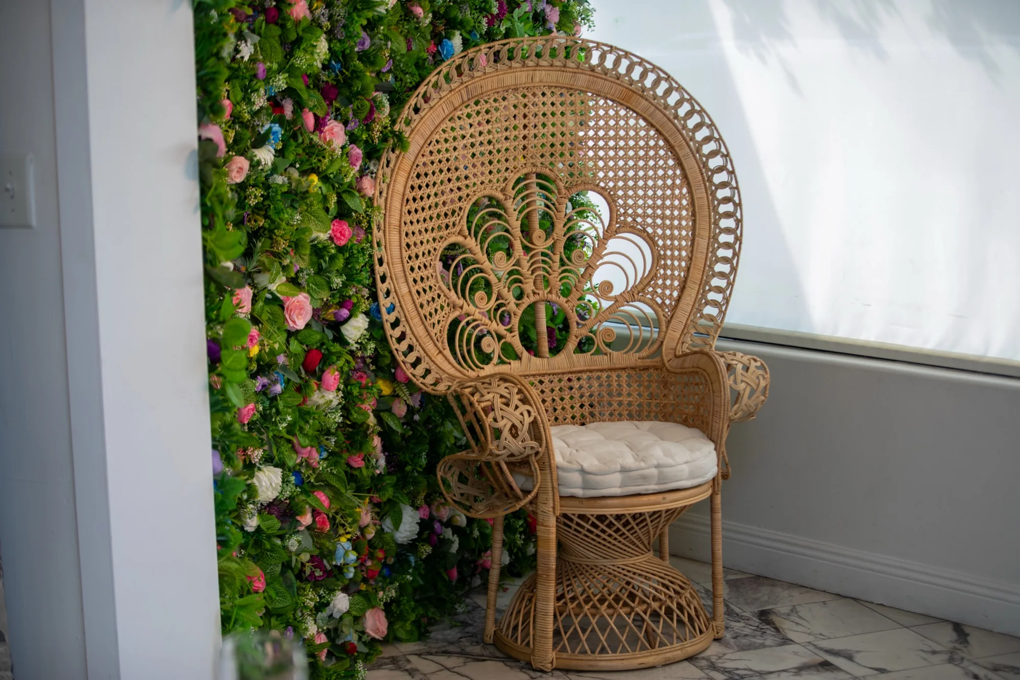 The peacock chair against the flower wall at Violet Cactus Petite